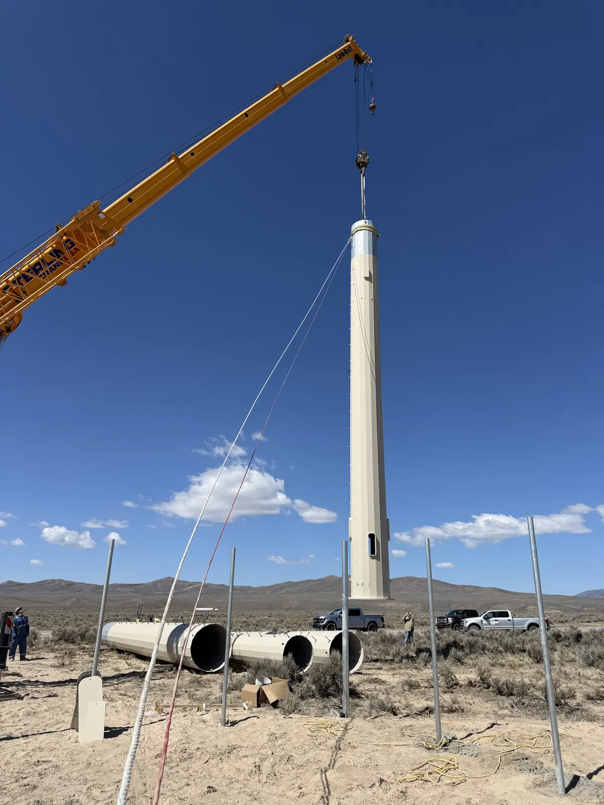 Crane setting a monopole section on a desert site
