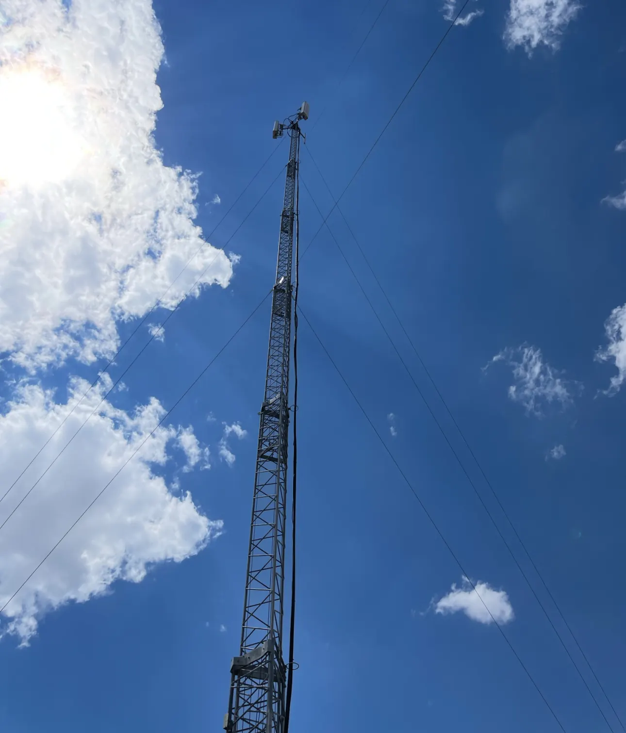 Guyed lattice tower with antennas against the sky